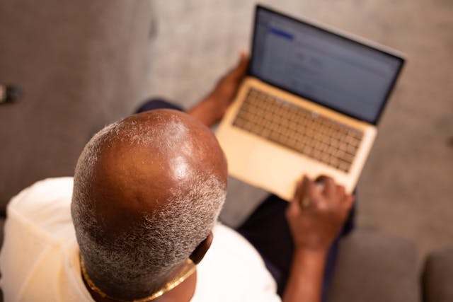 balding man sitting holding laptop